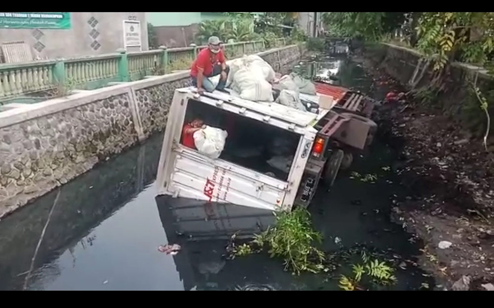 Sopir dan kernetnya gotong royong mengeluarkan paket dari dalam boks.