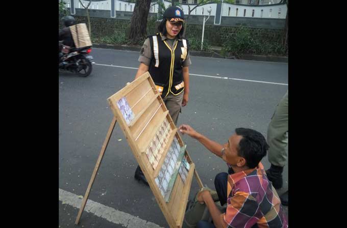 Salah satu petugas Banpol Satpol PP Kota Malang saat memberikan sosialisasi kepada penjual jasa penukaran uang agar tidak mangkal di tempat umum. foto: IWAN IRAWAN/ BANGSAONLINE