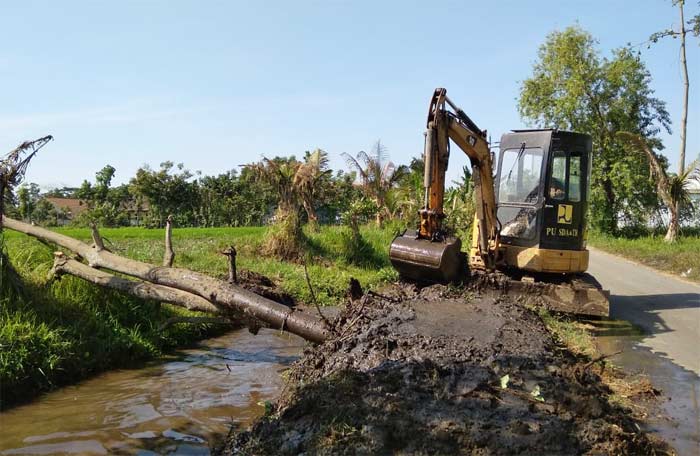 Alat berat sedang bekerja mengeruk sungai.