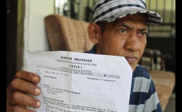 Salah seorang wali murid menunjukan surat edaran sari MTsN 1 Tanjunganom Nganjuk. foto: soewandito/BANGSAONLINE