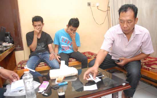 Dua pemuda beserta barang bukti saat diamankan di kos-kosan. (foto: rony suhartomo/BANGSAONLINE)