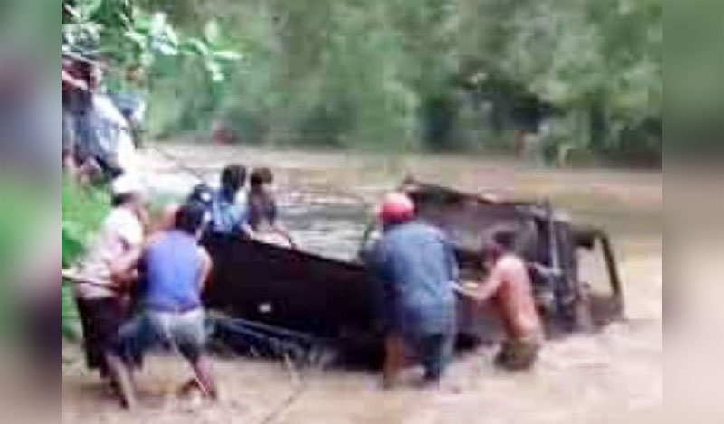 Para penambang dibantu warga berupaya mengevakuasi pikap yang terseret banjir.