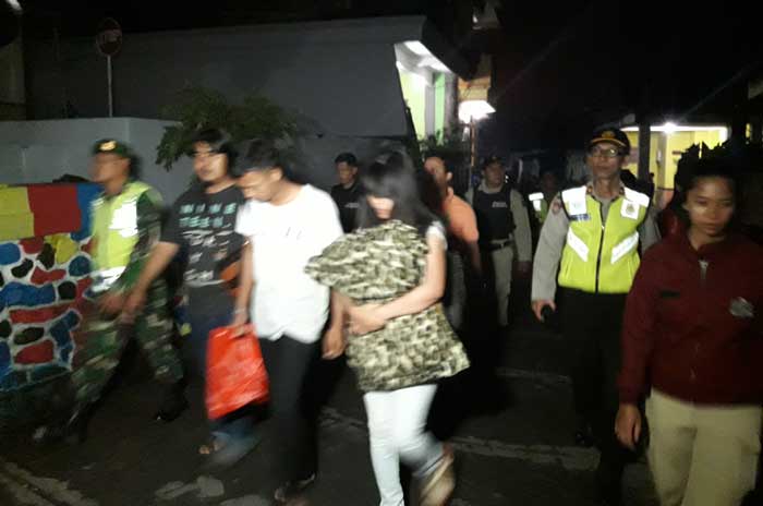 Salah satu pasangan mesum saat digiring dari vila ke dalam mobil untuk diangkut ke Pos Lantas 90 Alun-alun Batu. foto: ANIK/ BANGSAONLINE