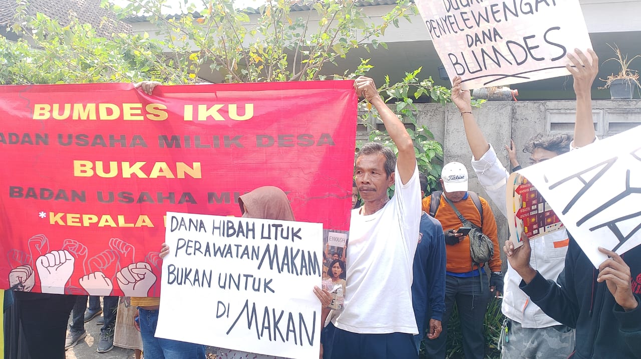 Warga Desa Boro saat membentangkan spanduk saat menggelar aksi protes