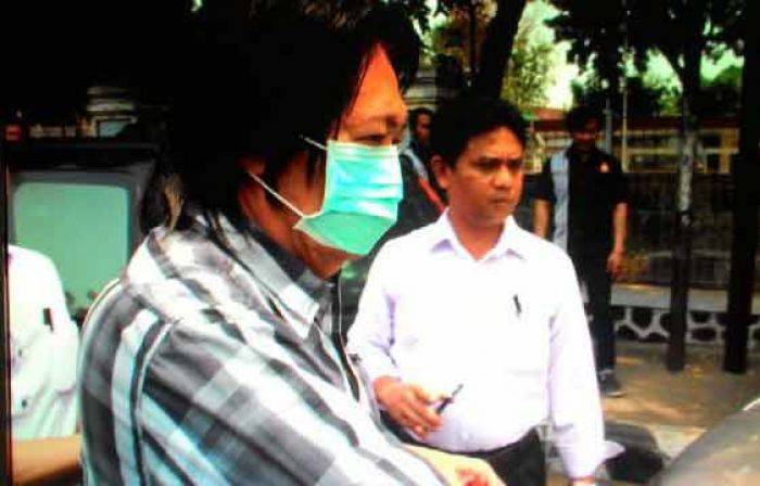Sony Sandra memakai masker saat digelandang untuk dibawa ke Mapolres Kediri Kota. foto: arif kurniawan/ BANGSAONLINE