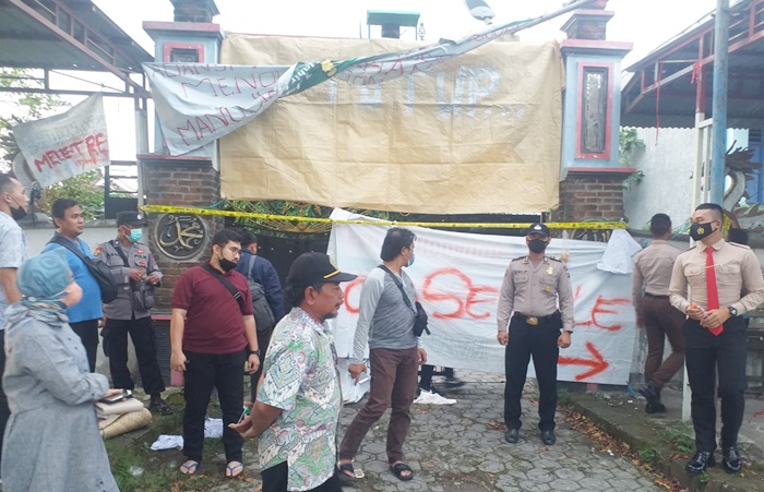 Petugas Polres Gresik didampingi pihak Desa Jogodalu saat memasang garis polisi di Pesanggrahan Keramat Ki Ageng. foto: ist.