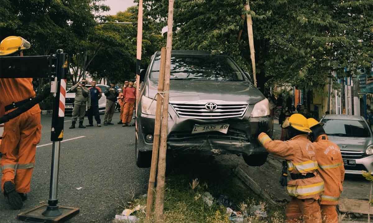 Petugas saat mengevakuasi mobil yang masuk ke kali di Surabaya.
