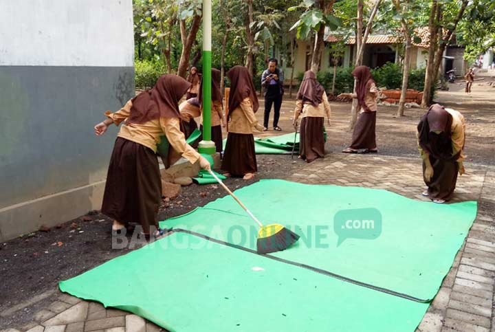 Para siswi kerja bakti membersihkan sekolah dari ulat bulu.