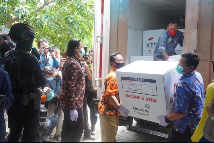 Para petugas menurunkan dan mengangkut vaksin yang baru datang, Senin. foto: ist  