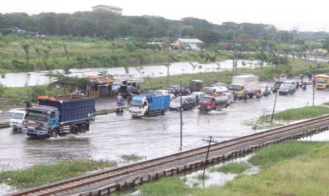 MERAMBAT: Kendaraan harus melambatkan laju saat melewati genangan air banjir di Jalan Raya Porong, Sidoarjo, Kamis (30/6) siang tadi. foto istimewa