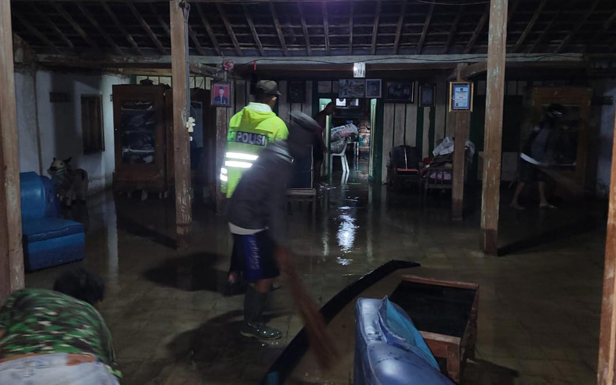 Anggota kepolisian ikut membantu bersih-bersih lumpur bekas banjir bandang.