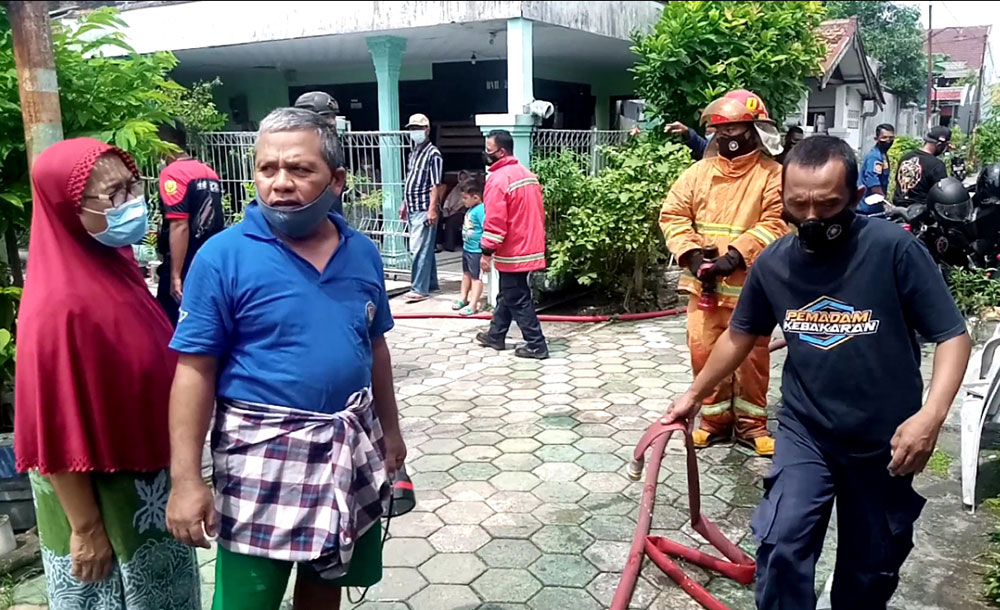 Petugas pemadam bersama warga usai berjibaku dengan api.