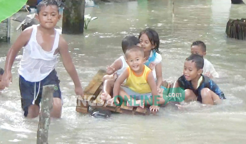 Para bocah tampak menikmati banjir untuk bermain air.