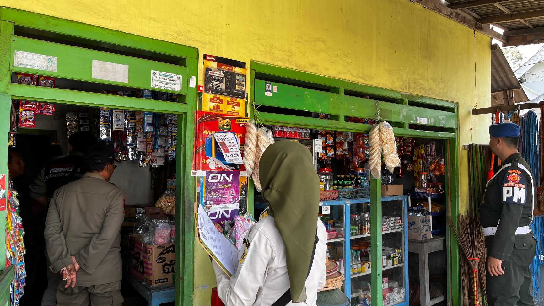 Petugas saat mendatangi salah satu toko kelontong