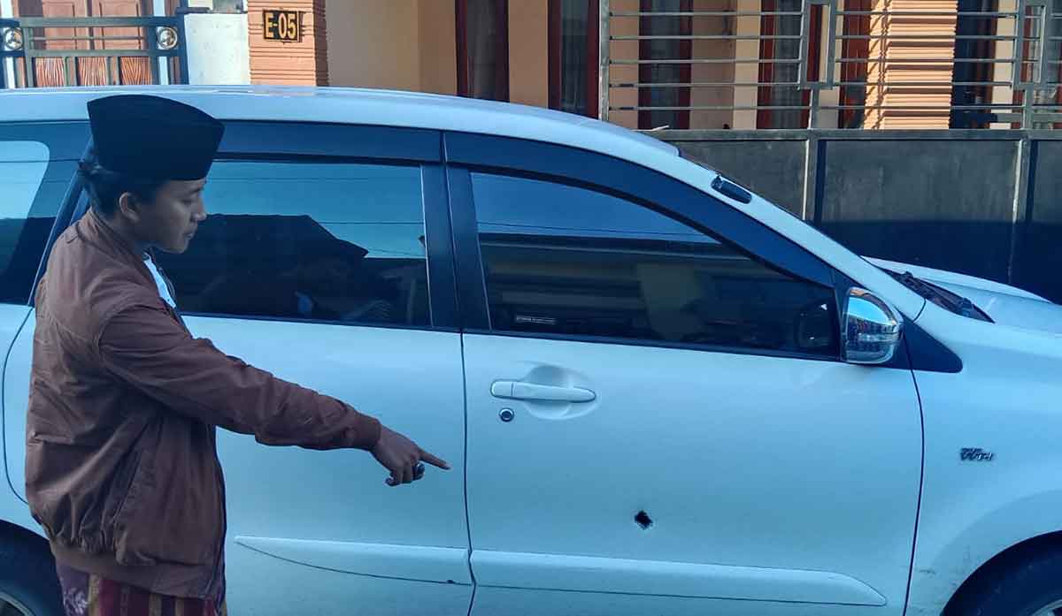 Kepala Desa Kelbung, Syaifuddin, saat menunjukkan bekas lubang di mobilnya yang diduga akibat proyektil senjata api.