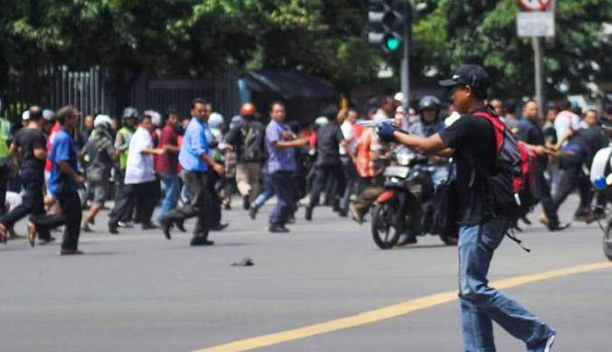 Seorang pelaku terlihat mengacungkan pistol setelah ledakan menghantam kawasan Jalan MH Thamrin, Jakarta Pusat, 14 Januari 2016. foto: KOMPAS