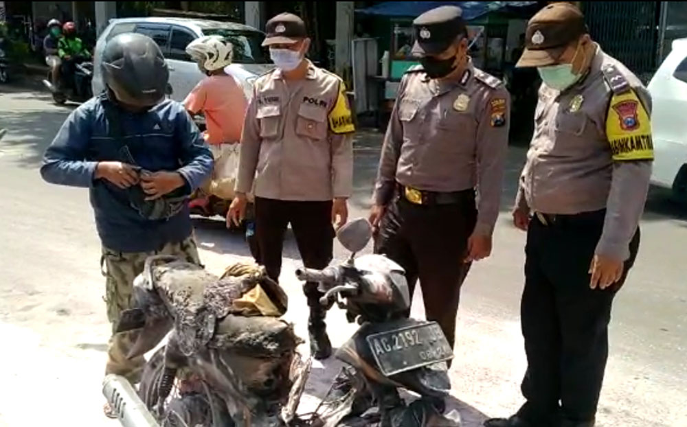 Nurkholis dan sepeda motornya yang terbakar saat akan dibantu evakuasi oleh petugas. Foto: Ist.