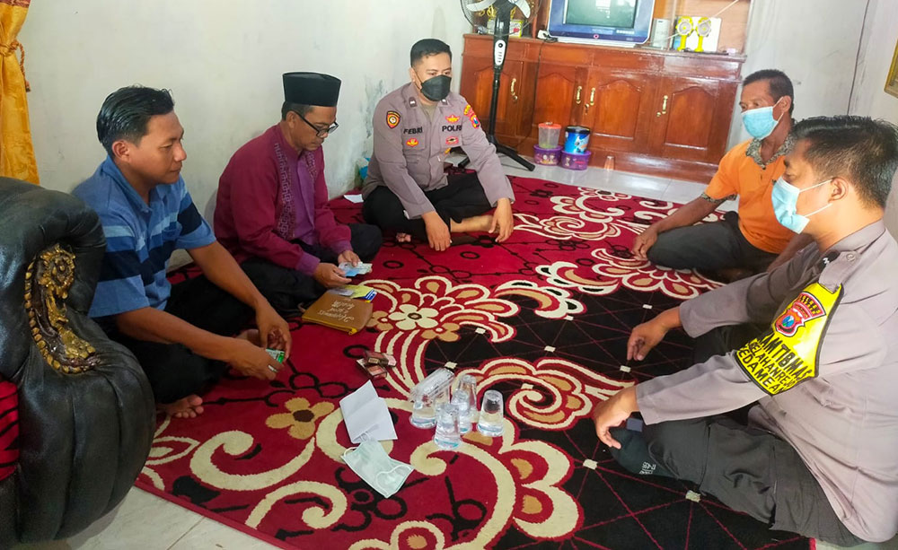 Bhabinkamtibmas Desa Katimoho Aipda Febriyanto bersama Kanit Binmas Polsek Kedamean Aipda Eko Subandi saat mendatangi rumah duka Almarhum Andik Suyanto. foto: ist.