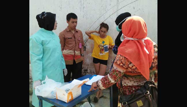 Pegawai Dinas Kesehatan Kota Blitar tengah memeriksa urine salah satu penghuni kos. foto: tri susanto/ BANGSAONLINE