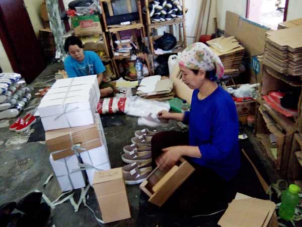 pekerja bagian packing sedang mengepak sepatu. foto:faratiti dewi/BANGSAONLINE