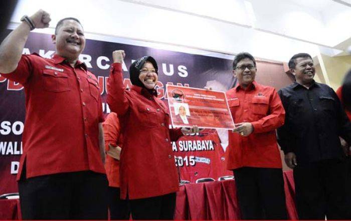 Sekjen DPP PDIP Hasto Kristianto menunjukkan KTA PDIP milik Tri Rismaharini. Tampak disampingnya Whisnu Sakti Buana. (maulana/BANGSAONLINE)