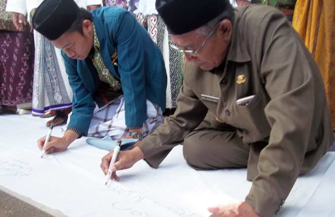 KH Abdul Wachid Badrus membubuhkan tanda tangan sebagai bentuk penolakan terhadap pelaksanaan Full Day School dari Mendikbud RI. foto: BAMBANG DJ/ BANGSAONLINE