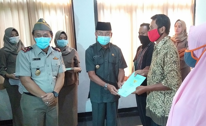 Pjs. Bupati Ponorogo Sujarno didampingi Kepala ATR/BPN Ponorogo Arya Ismana saat penyerahan sertifikat PTSL kepada warga secara simbolis.