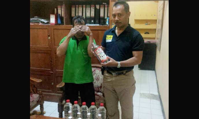 Tersangka hanya bisa menunduk saat miras yang disembunyikannya ditemukan petugas. foto: catur 