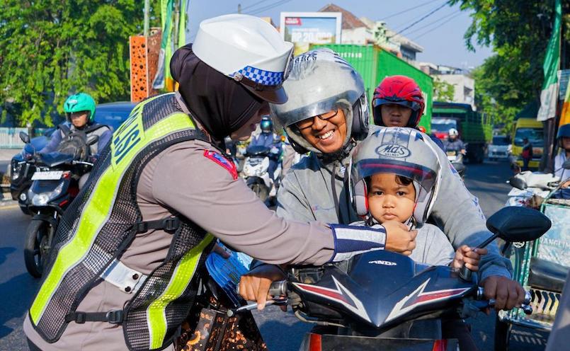Salah satu Anggota satlantas Polres Pasuruan saat membagikan helm SNI. Foto: Andy Fachrudin