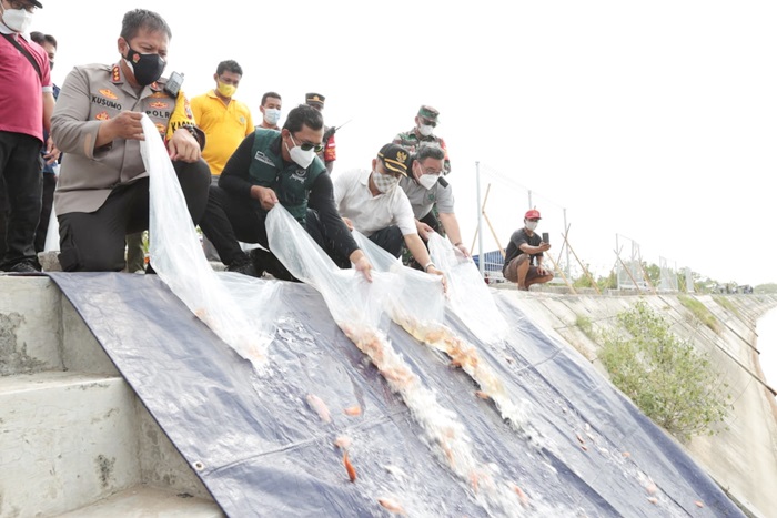 TEBAR: Bupati Gus Muhdlor dan Kapolresta Sidoarjo menebar ribuan ikan nila, di Long Storage Kalimati, Minggu (26/9/2021). foto: Kominfo Sidoarjo