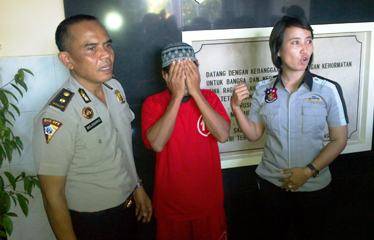 Tersangka diapit Kanit PPA dan Kasubag Humas. (foto: rusmiyanto/BANGSAONLINE)