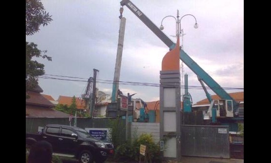 SALAHI ATURAN - Pekerja dengan alat berat sedang mengerjakan pembangunan gedung Universitas Muhammadiyah Gresik. (syuhud/BANGSAONLINE)