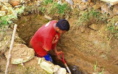 Seorang petugas makam sedang menggali kuburan.
