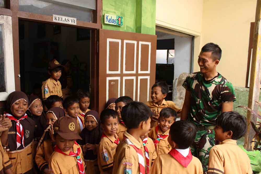Salah satu anggota Satgas TMMD Kodim 0809/Kediri bersama Siswa MI di Desa Gadungan. (Ist)