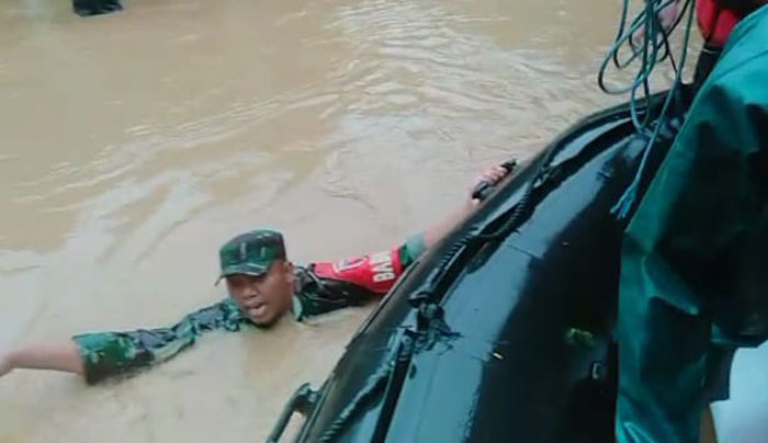 Babinsa Koramil 0818/16 Sumawe, Serda Siwo, saat berenang menyalurkan bantuan berupa makanan untuk korban banjir.