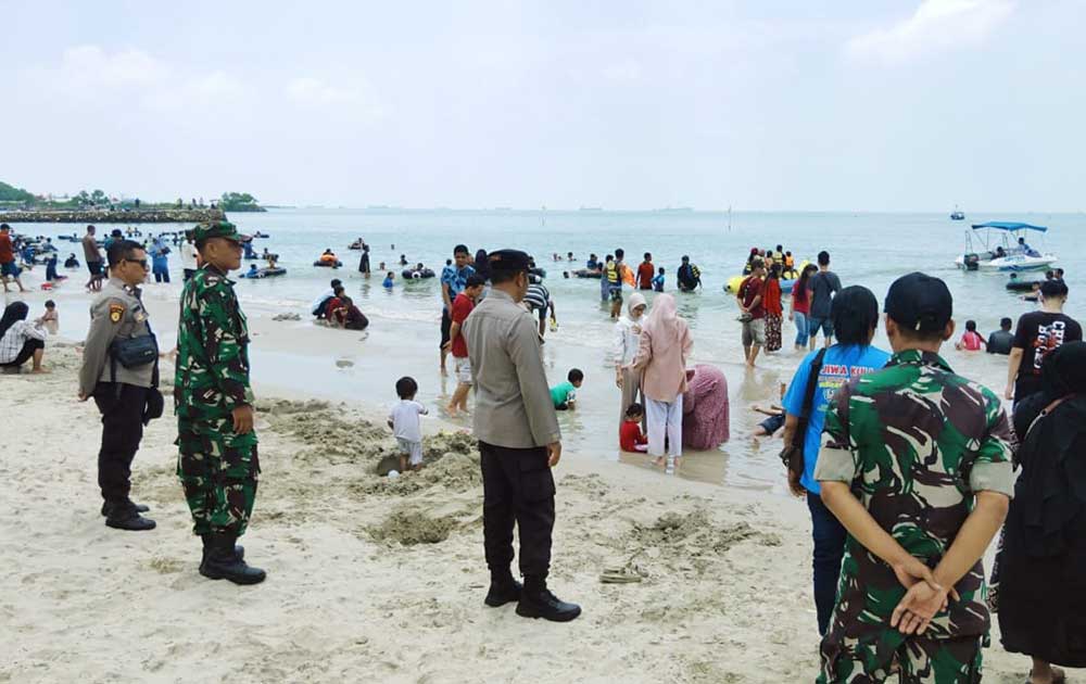 Personel Polres dan Kodim 0817/Gresik saat menjaga wisatawan yang tengah berlibur di Pantai Dalegan. Foto: Ist.