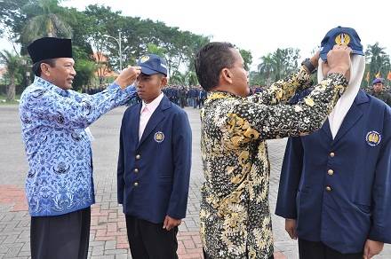 Bupati, Sambari HR saat menyematkan topi KKN mahasiswa Unesa. foto: SYUHUD/ BANGSAONLINE