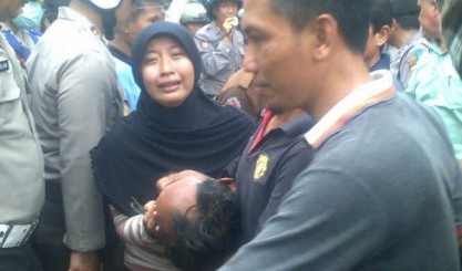 Salah satu warga yang pingsan segera digotong untuk diberikan pertolongan saat berusaha mempertahankan waduk Sepat. (Rusmiyanto/BANGSAONLINE)