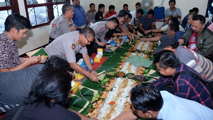 Kapolresta Sidoarjo beserta jajaran tampak guyub bersama para awak media, mengambil makanan yang dibungkus dan diberi alas daun pisang.