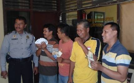 BARANG BUKTI – Empat warga menunjukkan barang bukti kartu remi dan uang tunai untuk berjudi didampingi petugas, di Mapolsek Taman, Senin (8/9/2014). Foto : catur andy/BangsaOnline