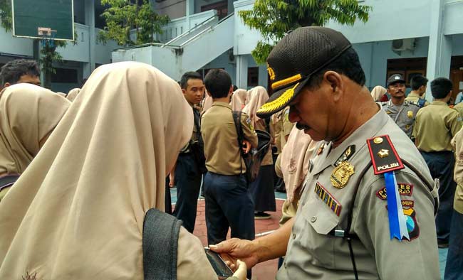 Petugas kepolisian memeriksa Hp tiap siswa untuk mencegah konten-konten porno. foto: catur 