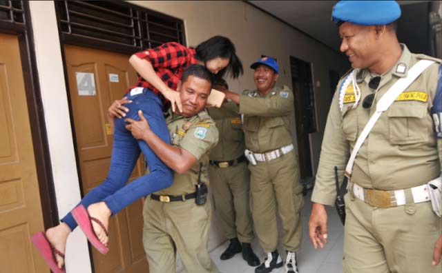 Terjaring razia, anggota Satpol PP Kota Surabaya menggendong anaknya sendiri dari kamar hotel untuk diajak pulang. foto: tribunkota.com