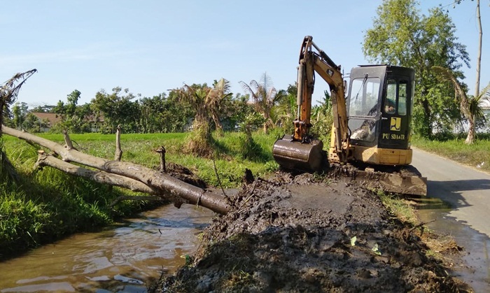 Alat berat sedang mengeruk salah satu irigasi.