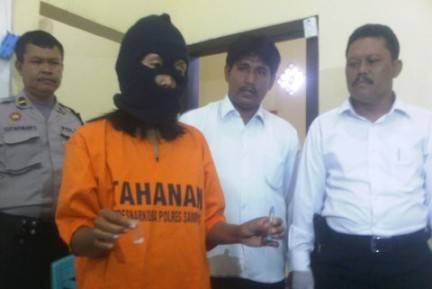 Tersangka saat menunjukkan barang bukti berupa satu poket sabu-sabu. (foto: bahri/BANGSAONLINE)