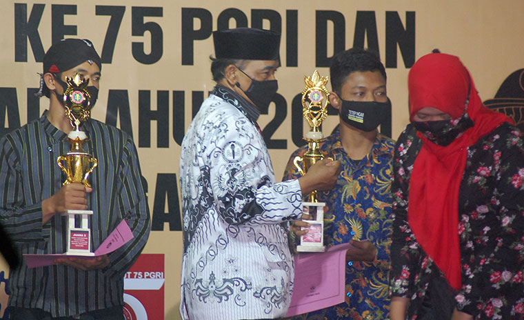 Ketua PGRI Kabupaten Trenggalek Drs. Munib M.Pd., saat memberikan hadiah pada peserta lomba di peringatan HUT PGRI dan Hari Guru Nasional. foto: HERMAN/ BANGSAONLINE