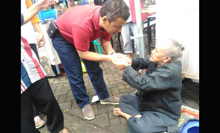 Wan Edi saat menyapa seorang perempuan tua pengamen jalanan, sewaktu ketemu di Pasar Pagi Velodrome Sawojajar, Minggu (14/1). Foto: IWAN I/BANGSAONLINE