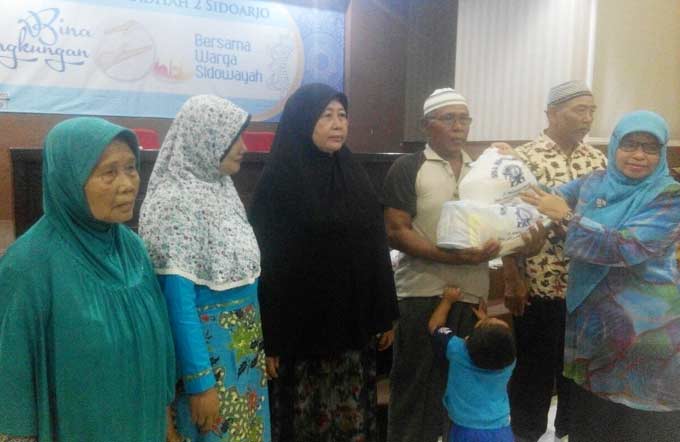 BERBAGI: Kepala Smamda Wigatinigsih menyerahkan parcel Lebaran kepada warga Sidowayah saat Bukber, Senin (19/6) petang. foto: MUSTAIN/ BANGSAONLINE