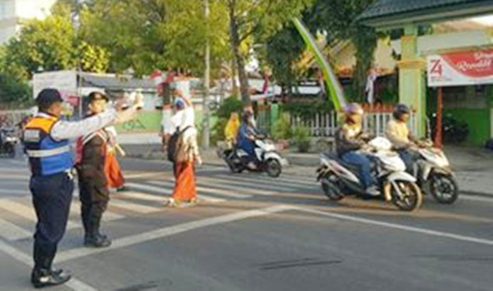 Petugas Dishub dan Polres Mojokerto Kota sedang membantu menyeberangkan para pelajar.