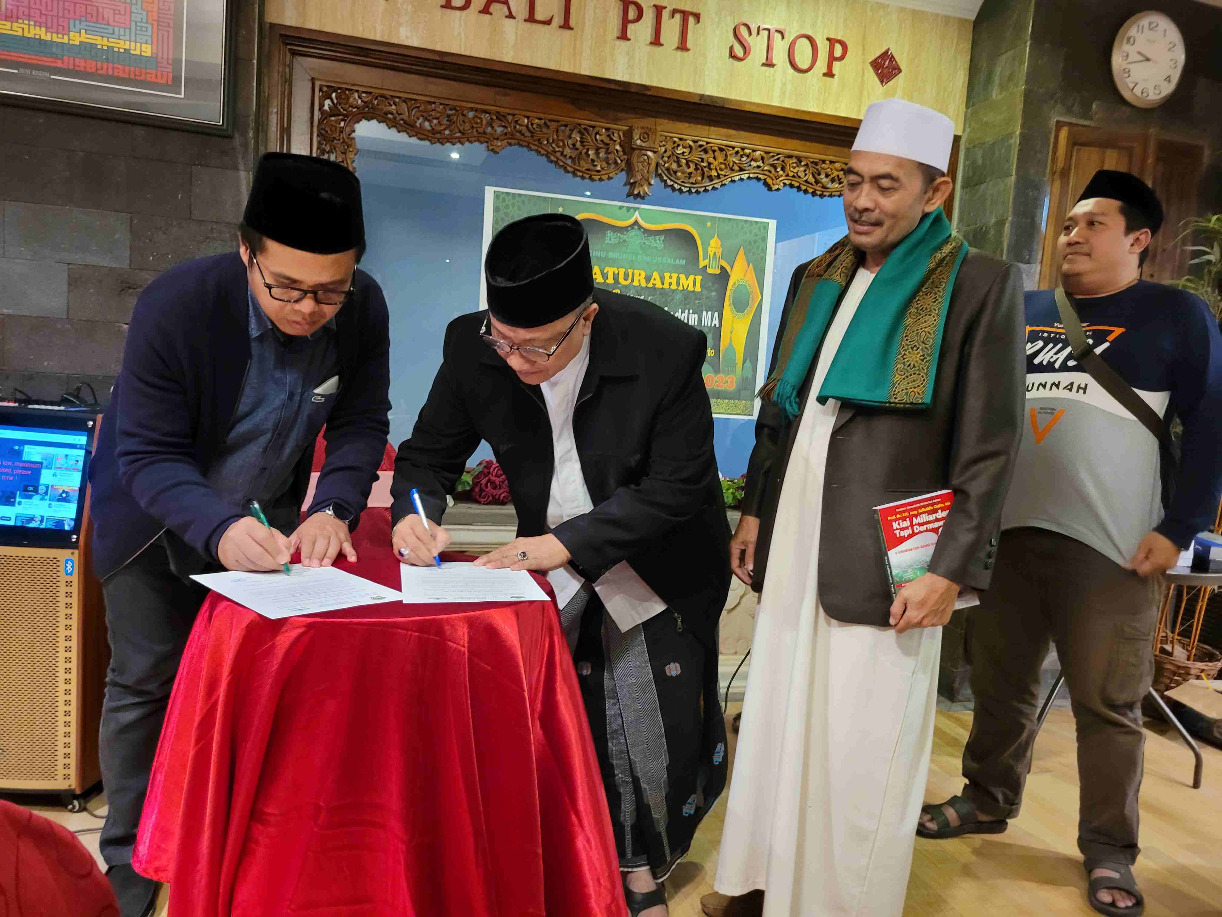 Rektor Universitas KH Abdul Chalim, Dr KH Mauhibur Rokhman (Gus Muhhib) dan Ketua PCINU Brunei Darussalam KH Ahmad Dhofir menandatangani kesepakatan kerjasama disaksikan Rais Syuriah PCINU Brunei KH Affandi dan Wakil Rektor  Universitas KH Abdul Chalim, Dr Ing Fadly Usman,  usai acara bedah buku Kiai Miliarder Tapi Dermawan karya M. Mas