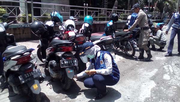 DAPAT BANYAK: Petugas dari Dishub saat menggembosi ban motor yang parkir sembarangan. foto: devi/ BANGSAONLINE